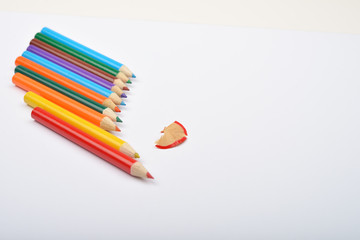 Close up of arranged colored pencils with pencil shavings on whi