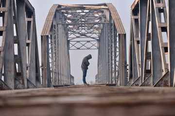 Portrait of sad teenager in depression sitting on the bridge at
