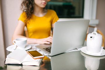 Hands over laptop with smartphone notepad and tea in cafe