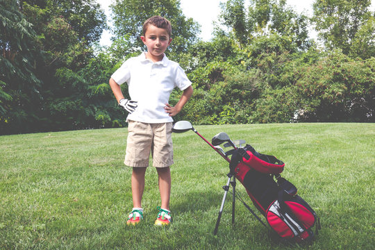 Little boy golfer with his golf bag on the fairway