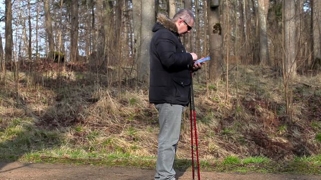 Hiker with walking sticks take pictures on tablet PC