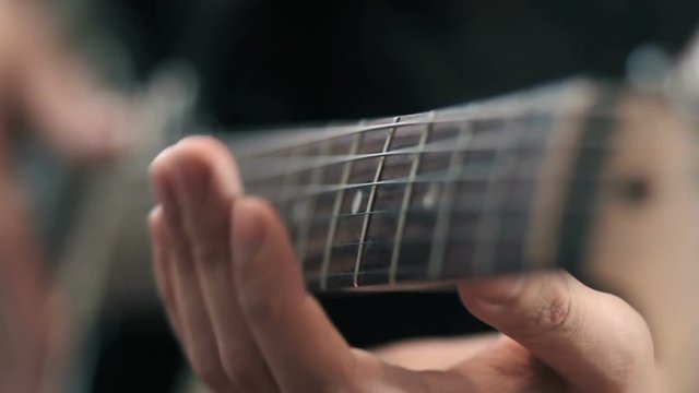 close up of hands playing a guitar
