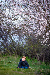 Little baby boy with her young mother in the blossom garden