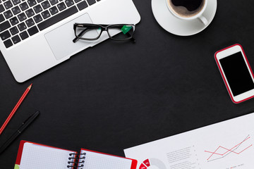 Office desk with laptop, coffee, notepad and phone
