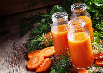 Freshly squeezed juice of carrots in glass bottles, vintage wood