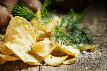 Salted potato chips with herbs on a wooden table vintage, countr