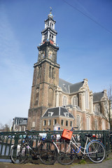 Naklejka na ściany i meble Westerkerk in Amsterdam with bicycles in the foreground. This blue-crowned Protestant church, built in 1631, has become a symbol of the Jordaan.