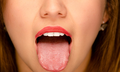 Closeup young womans open mouth with tongue sticking out