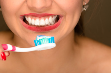 Closeup young womans mouth showing white healthy teeth and holding toothbrush in front