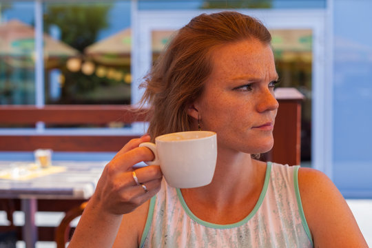 Young woman on a cafe terrace in the summer enjoy a delicious co