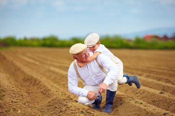 laughing grandfather and grandson having fun on spring field, countryside