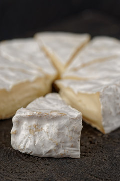 Cut wheel of brie cheese on wooden surface