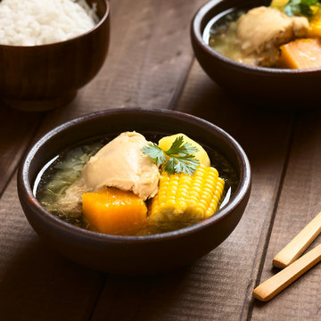 Traditional Chilean Cazuela de Pollo soup made of chicken, sweetcorn, pumpkin and potato, garnished with coriander, photographed with natural light (Selective Focus, Focus in the middle of the soup)