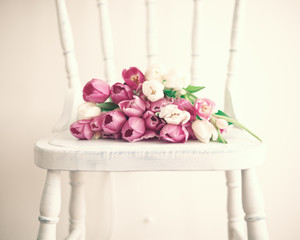 Pink and white tulips in a vintage white wood chair