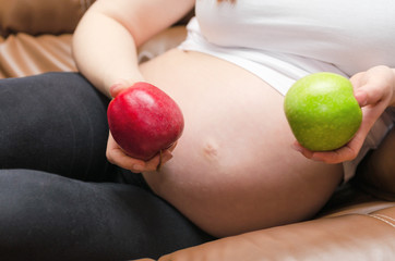 pregnant woman holding apple close about belly