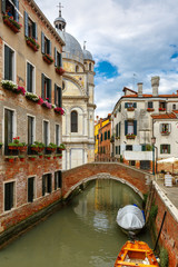 Fototapeta na wymiar Colorful narrow lateral canal, church Santa Maria dei Miracoli and pedestrian bridge in the sestiere of Cannaregio at morning, in Venice, Italia
