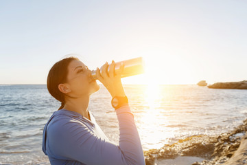 Woman drinking water on beach