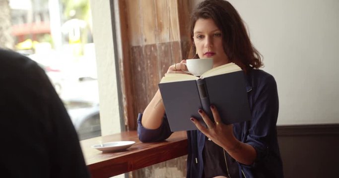Girl Drinking Coffee and Reading Book in Cafe