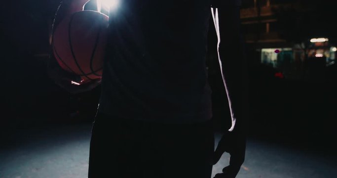 Male basketball Player Holding ball on hip in Evening