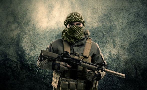 Portrait of a heavily armed masked soldier with grungy backgroun