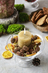 Candle holder decorated with cones and dried fruits.