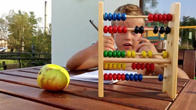 Little boy counting and doing homework outside
