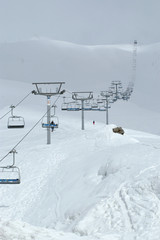 Ski. Lift in the snowing High Mountains. Clouds. Wide landscape