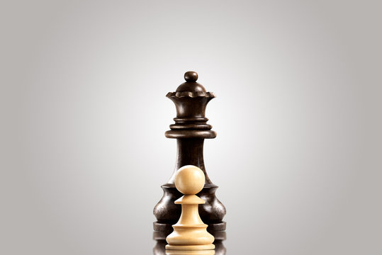 Rivalry / Leadership and bravery concept; white wooden single pawn staying against a black queen.