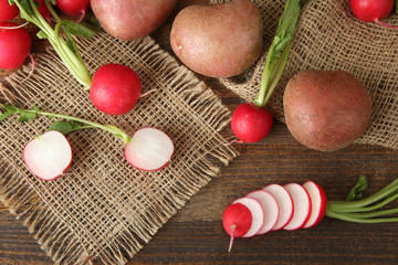 red potatoes with chopped radishes on sackcloth on wooden brown background