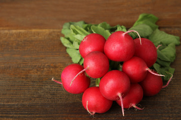 bunch of fresh radishes with the green tops on wooden brown background