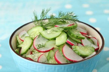 salad of radishes and cucumber with greens in bowl on fabric with polka dots