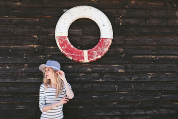 woman in a hat standing near a wooden wall with a lifeline