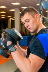 portrait of a man exercising with dumbbells in a gym