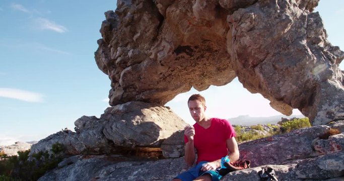 Man Resting From Outdoor Activity And Eating Energy Bar