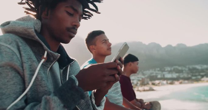 African American Skater Sitting and Looking at Smartphone Outsid