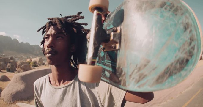 Close up of African American Skater Holding Skateboard Outside