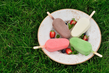 plate of ice cream on the grass. Glazed colorful popsicle. Summe