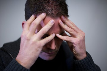 Man holdings hands on head due to headache burn-out stress and depressions