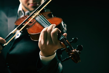 Musician play violin on dark background, close up