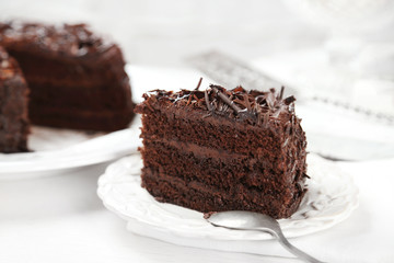 Sliced chocolate cake on wooden table, on light background