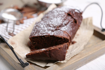 Chocolate sliced cake with icing and powdered sugar on a tray