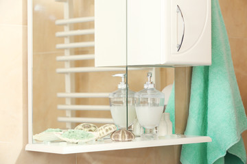Liquid soap with green salt and shells on a shelf in bathroom