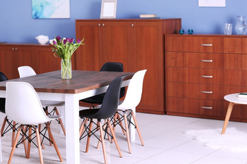 Modern living room. Furniture set with table and chairs. Bouquet of beautiful white and purple tulips on the table