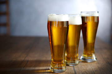 Three glasses of light beer on wooden table