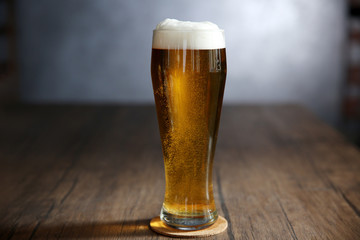 Glass of light beer on wooden table