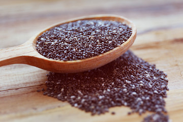 Spoon of chia seeds on wooden background