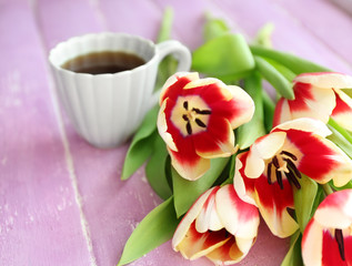 Bouquet of variegated tulips with cup of coffee on wooden background