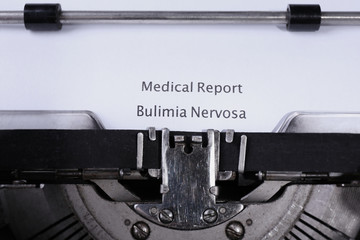 Old typewriter and inserted white sheet of paper with medical report on bulimia