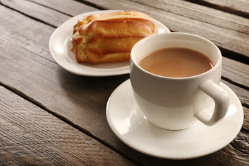 Milk tea with eclairs on wooden background.