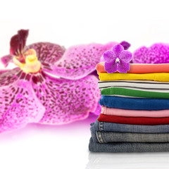 Pile of colorful clothes and purple orchid flower  background.